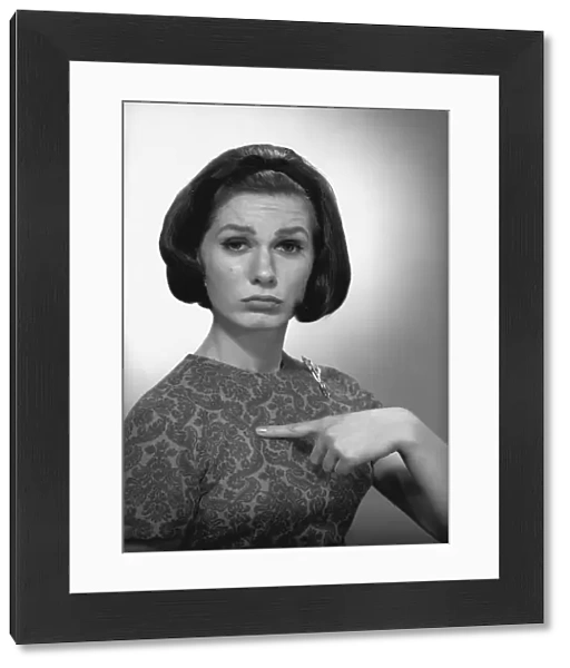 Woman pointing on herself in studio, (B&W), portrait