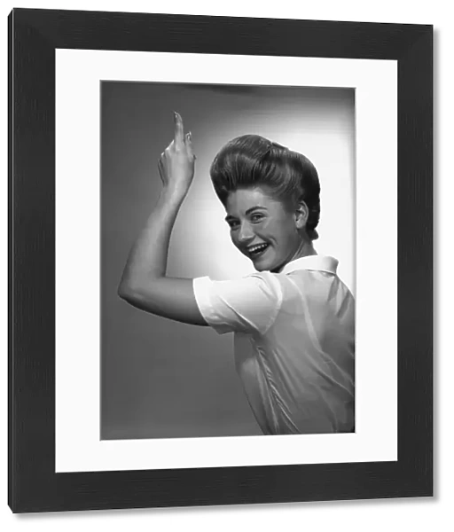 Woman pointing up in studio, (B&W), portrait