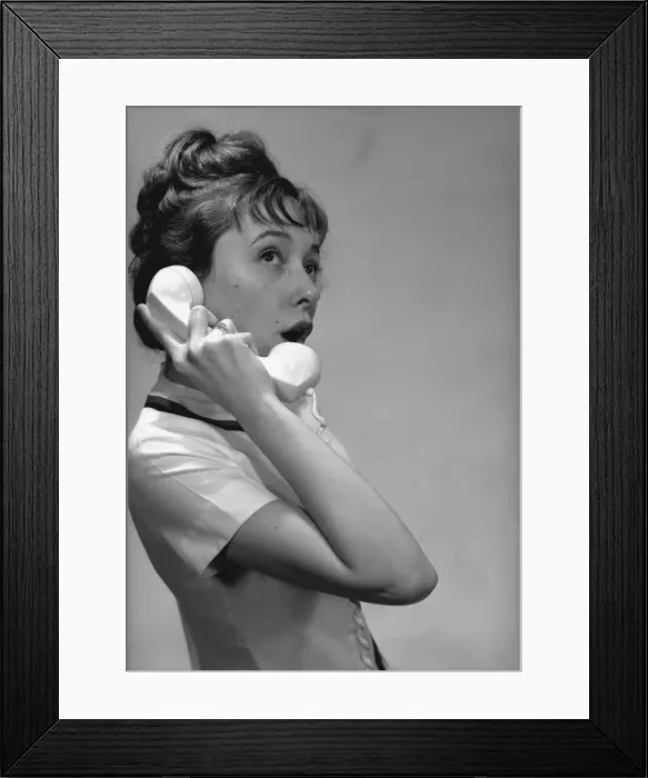 Framed Print : Young woman talking on phone in studio, (B&W) Framed Print : Young woman talking on phone in studio, (B&W)