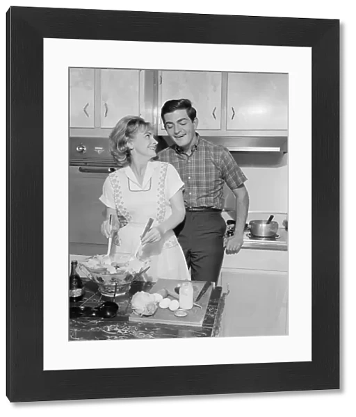 Mid adult couple in kitchen, woman preparing salad