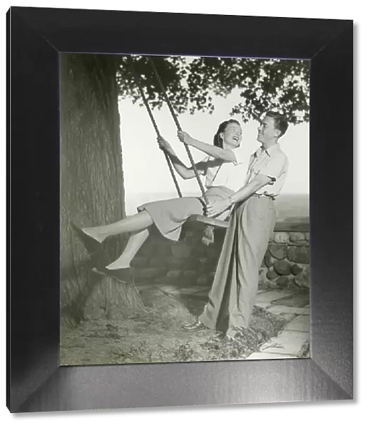 Couple playing on tree swing