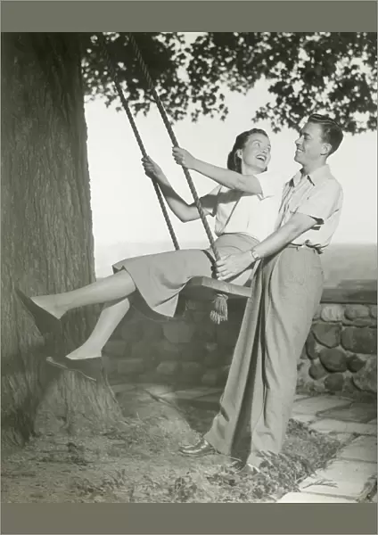 Couple playing on tree swing