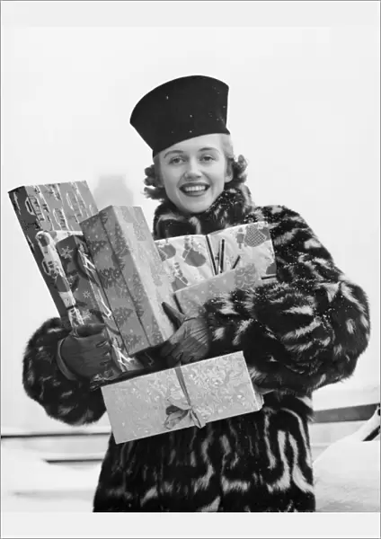 Woman in fur coat holding Christmas gifts