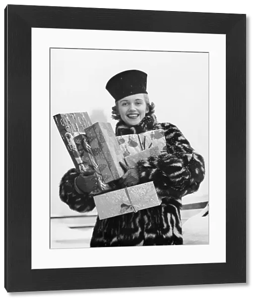 Woman in fur coat holding Christmas gifts