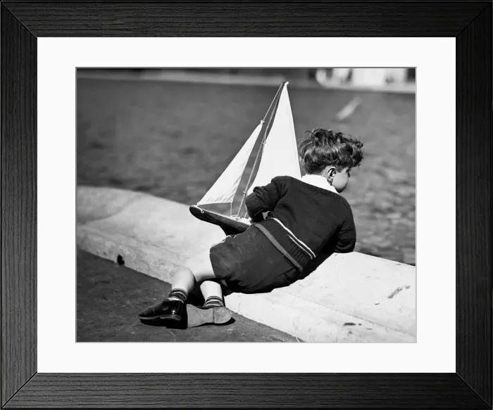Framed Print : Boy playing with toy sailboat Framed Print : Boy playing with toy sailboat