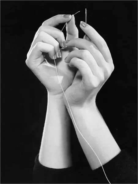 Womans hands threading needle