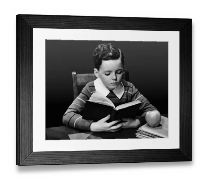 Framed Print : Boy reading book at desk Framed Print : Boy reading book at desk