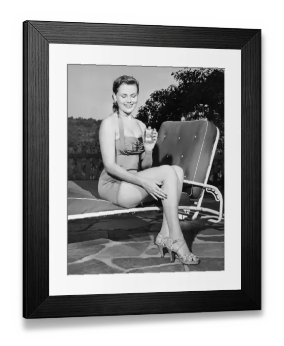 Framed Print : Woman on lawn chair applying oil to her legs