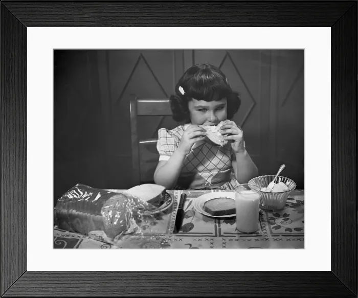 Framed Print : Portrait of little girl eating buttered toast Framed Print : Portrait of little girl eating buttered toast