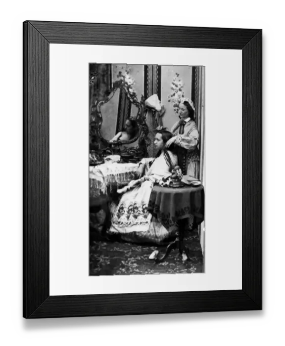 Framed Print : Hair Help. circa 1865: A seated lady having her hair attended to by a servant Framed Print : Hair Help. circa 1865: A seated lady having her hair attended to by a servant