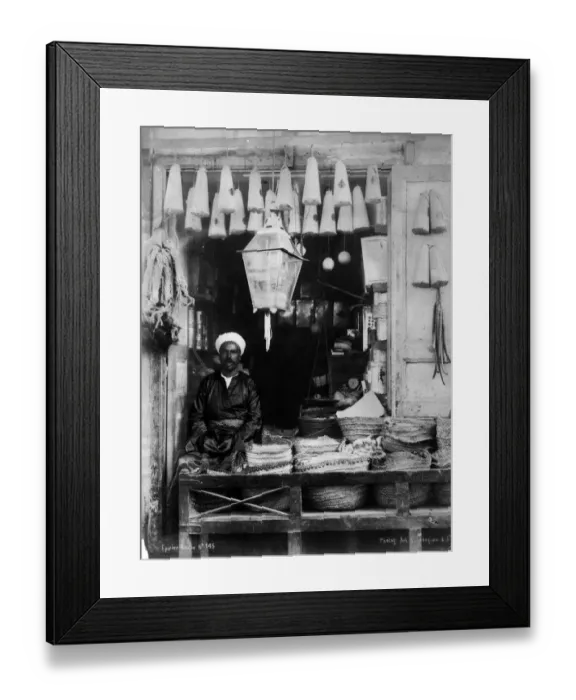Framed Print : Shopfront. circa 1900: An African shopkeeper selling lanterns and household goods