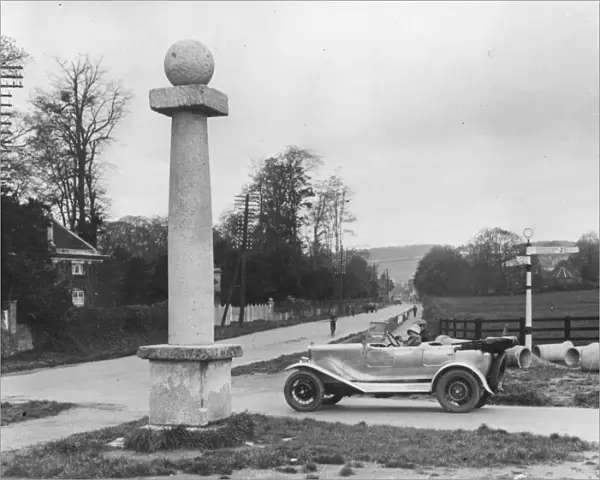 Milestone. 1910: A car approches an old milestone at the road fork just