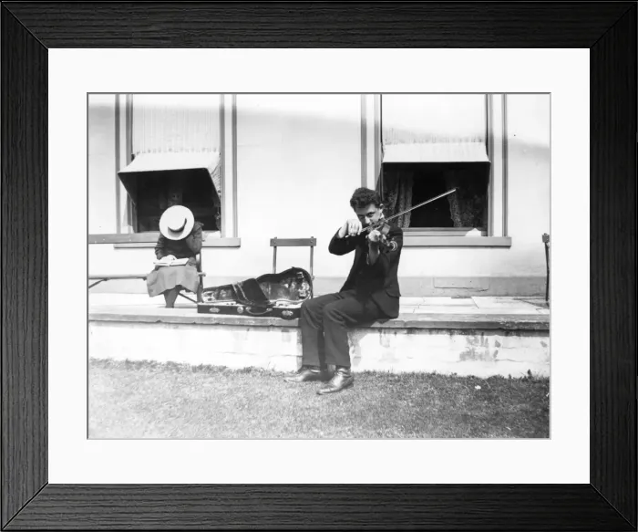 Framed Print : Violinist. circa 1908: A youth playing the violin, while sitting on a wall outsde a house Framed Print : Violinist. circa 1908: A youth playing the violin, while sitting on a wall outsde a house