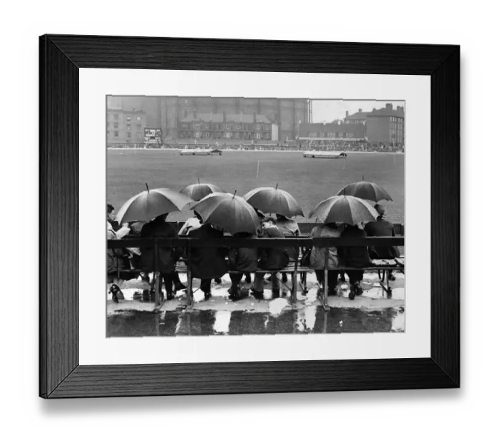 Framed Print : Oval Rain. circa 1946: A group of spectators sit underneath umbrellas in the rain Framed Print : Oval Rain. circa 1946: A group of spectators sit underneath umbrellas in the rain