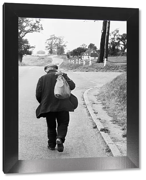 Hard Road. 25th July 1953: An old mand trudges up a road, sack on his back