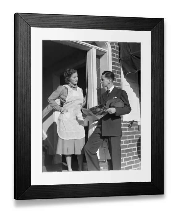 Framed Print : Salesman At Door Of A House Wife Showing Her A Bro