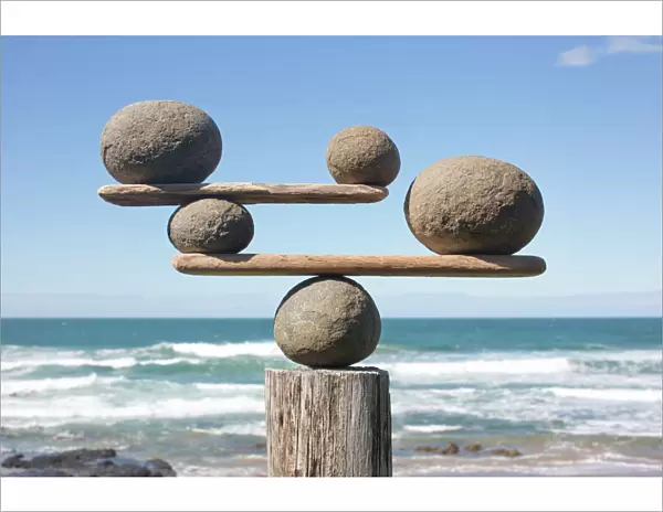 Rocks balancing on driftwood, sea in background