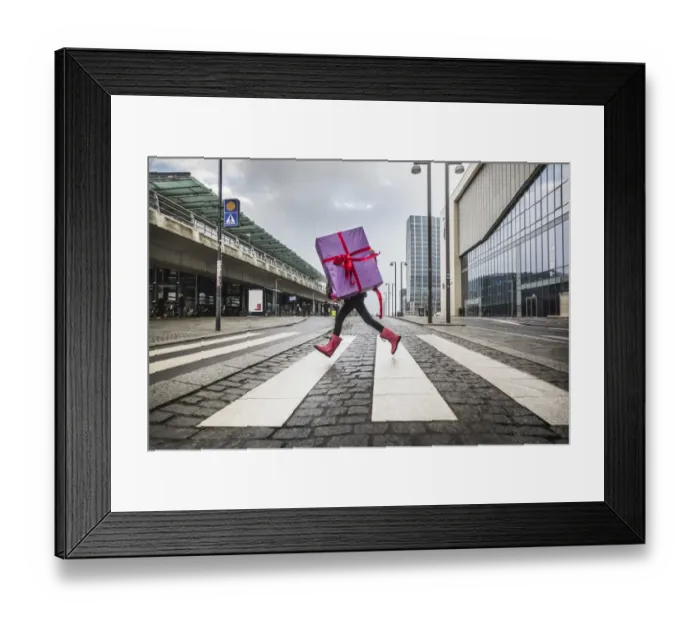 Framed Print : Young girl running with large gift on street Framed Print : Young girl running with large gift on street