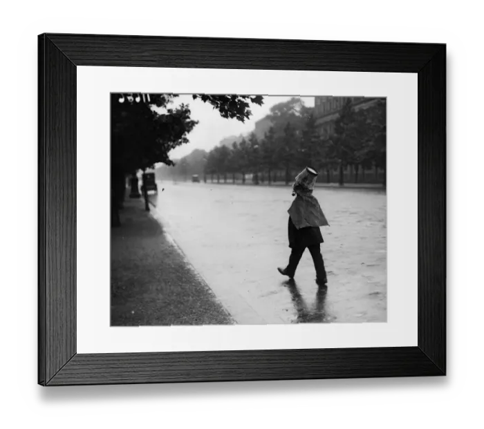 Framed Print : Rainswept. June 1919: A window cleaner keeps the rain off his head by wearing Framed Print : Rainswept. June 1919: A window cleaner keeps the rain off his head by wearing