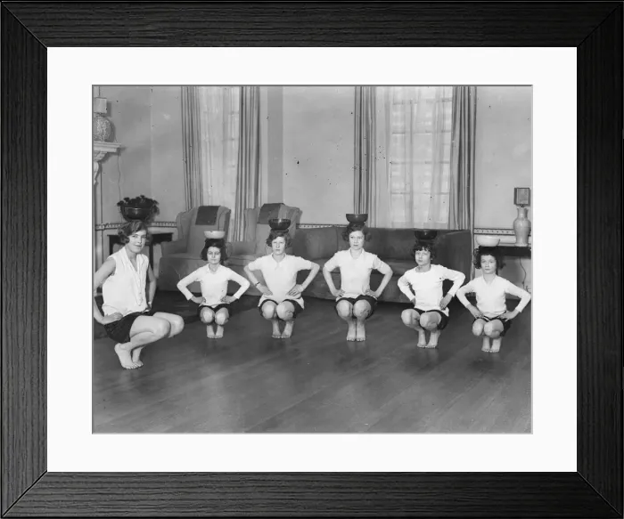 Framed Print : Line of girls (7-12) exercising with bowls on heads (B&W) Framed Print : Line of girls (7-12) exercising with bowls on heads (B&W)