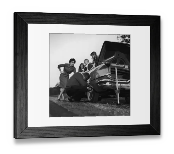 Framed Print : Mother and children (3-8) watching father change flat tire (B&W) Framed Print : Mother and children (3-8) watching father change flat tire (B&W)