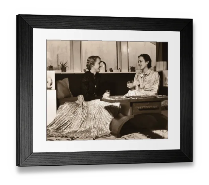 Framed Print : Two Women Sitting on Sofa with Drinks, Chatting Framed Print : Two Women Sitting on Sofa with Drinks, Chatting