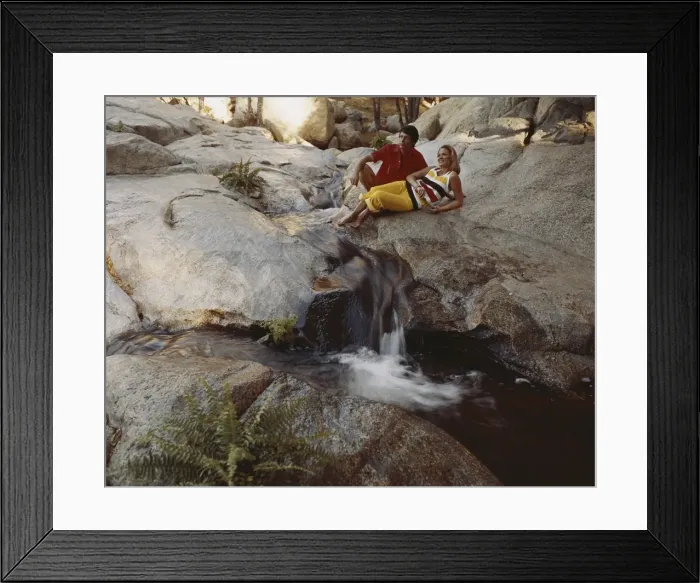 Framed Print : Couple leaning on rock above waterfall Framed Print : Couple leaning on rock above waterfall
