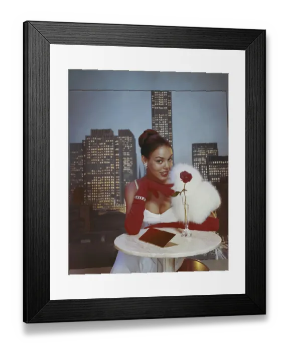 Framed Print : Young woman wearing fur boa sitting at table, smiling, portrait Framed Print : Young woman wearing fur boa sitting at table, smiling, portrait