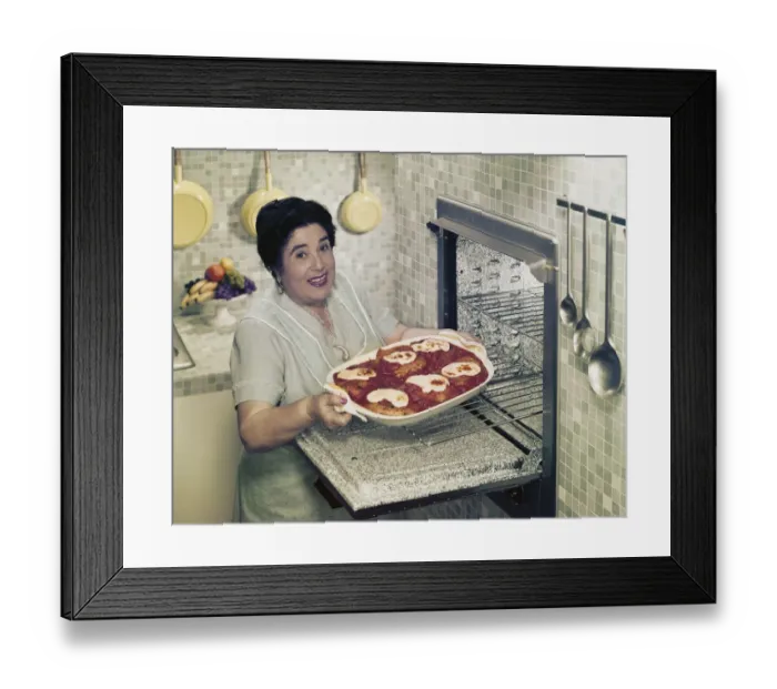 Framed Print : Mature woman putting food into oven, smiling, portrait Framed Print : Mature woman putting food into oven, smiling, portrait