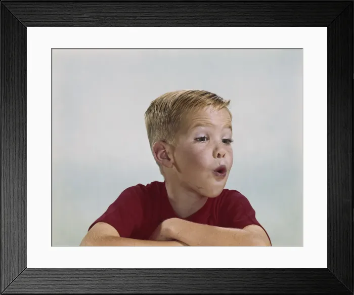 Framed Print : Boy blowing, close-up Framed Print : Boy blowing, close-up