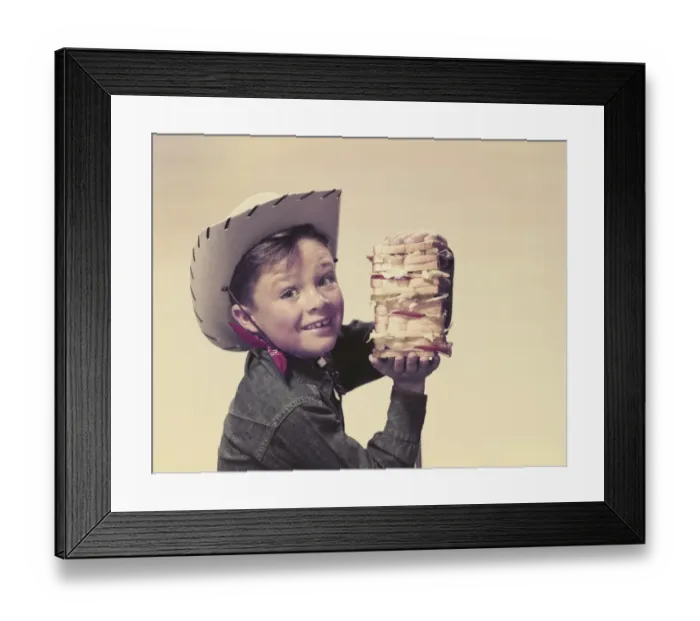Framed Print : Cowboy holding sandwich, smiling, portrait