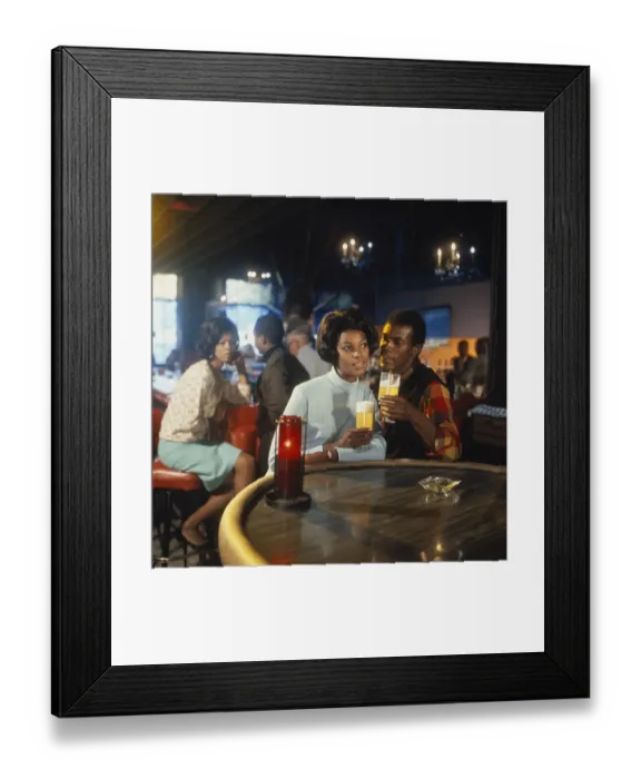 Framed Print : Young couple sitting at table holding glass of beer Framed Print : Young couple sitting at table holding glass of beer