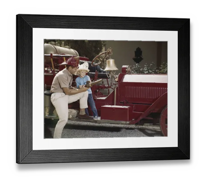 Framed Print : Father and son holding fire hose, smiling Framed Print : Father and son holding fire hose, smiling