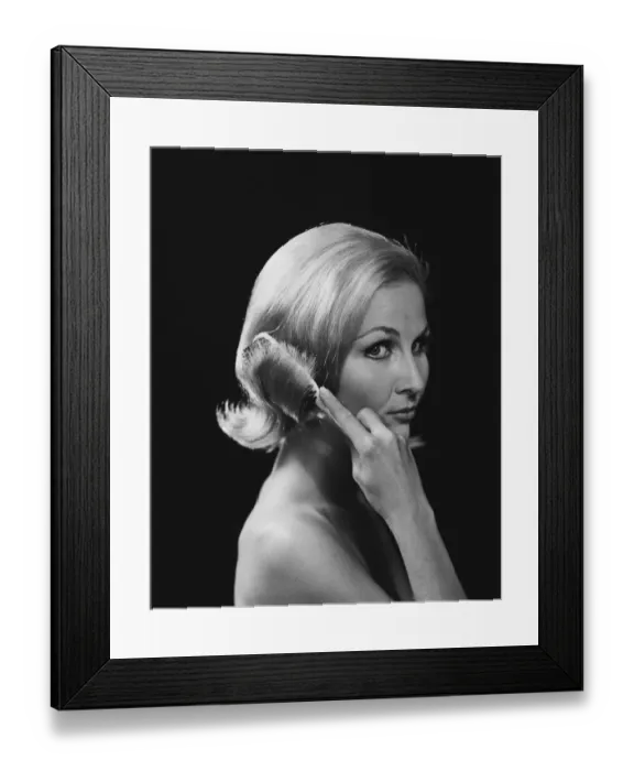 Framed Print : Woman combing hair against black background, close-up Framed Print : Woman combing hair against black background, close-up