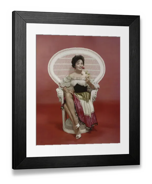 Framed Print : Young woman sitting on chair holding rose, smiling, portrait Framed Print : Young woman sitting on chair holding rose, smiling, portrait