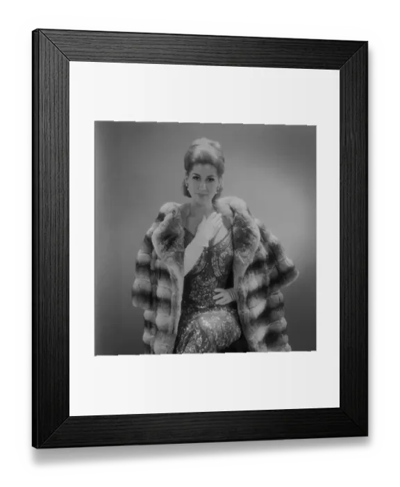 Framed Print : Woman wearing fur coat sitting against grey background