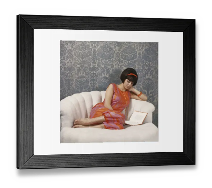 Framed Print : Young woman reading book on sofa Framed Print : Young woman reading book on sofa
