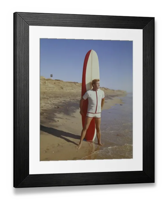 Framed Print : Surfer holding surfboard on beach