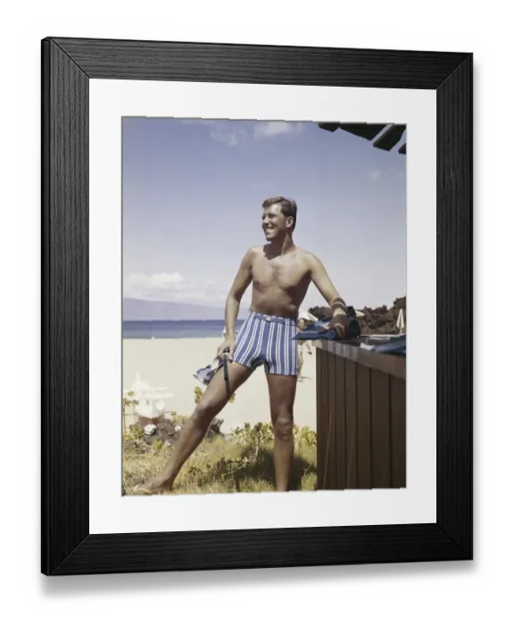 Framed Print : Man holding snorkel and flippers on beach, smiling