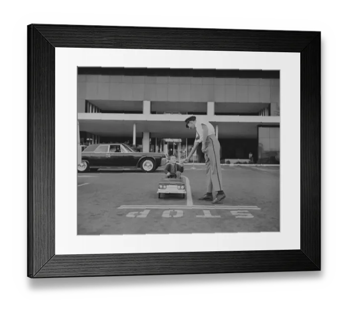 Framed Print : Boy sitting in toy car giving paper to traffic police officer Framed Print : Boy sitting in toy car giving paper to traffic police officer