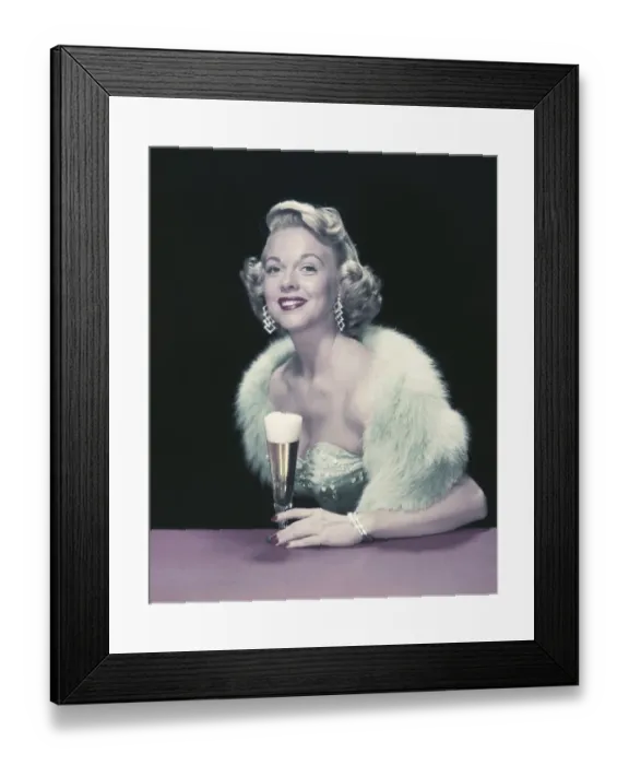Framed Print : Young woman holding glass of beer, smiling, portrait Framed Print : Young woman holding glass of beer, smiling, portrait
