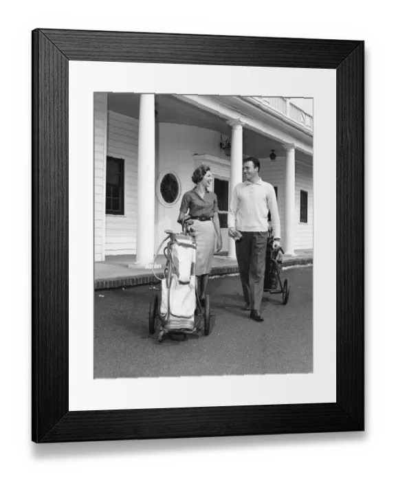 Framed Print : Couple walking with golf carts in front of clubhouse Framed Print : Couple walking with golf carts in front of clubhouse