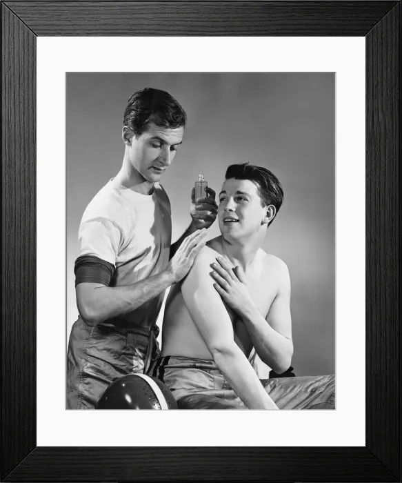 Framed Print : Two men, one rubbing liniment on others shoulders Framed Print : Two men, one rubbing liniment on others shoulders