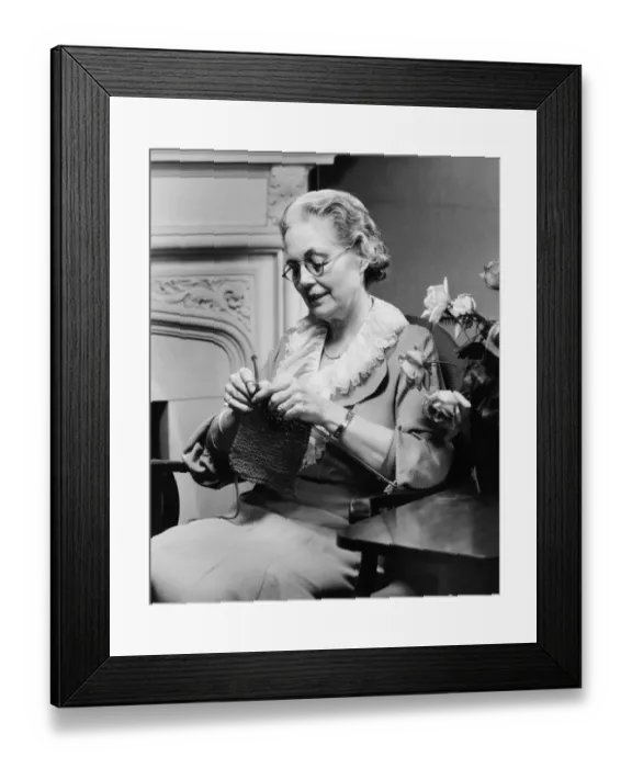 Framed Print : Senior woman knitting in living room, (B&W) Framed Print : Senior woman knitting in living room, (B&W)