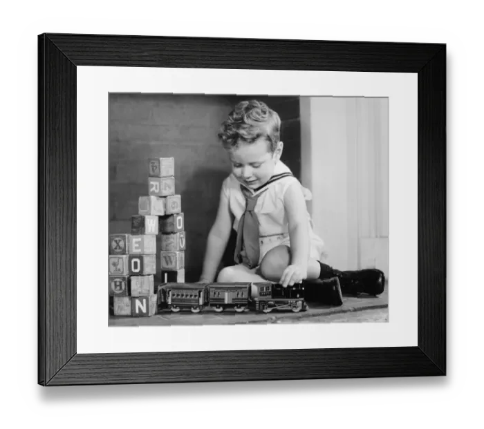 Framed Print : Boy (4-5) playing with model train set on floor, (B&W) Framed Print : Boy (4-5) playing with model train set on floor, (B&W)