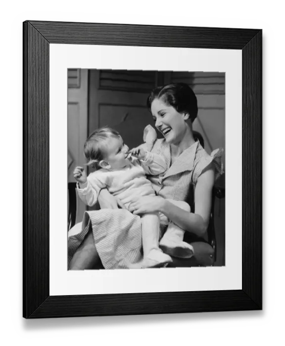 Framed Print : Mother laughing with child (6-12 months) on laps, (B&W) Framed Print : Mother laughing with child (6-12 months) on laps, (B&W)