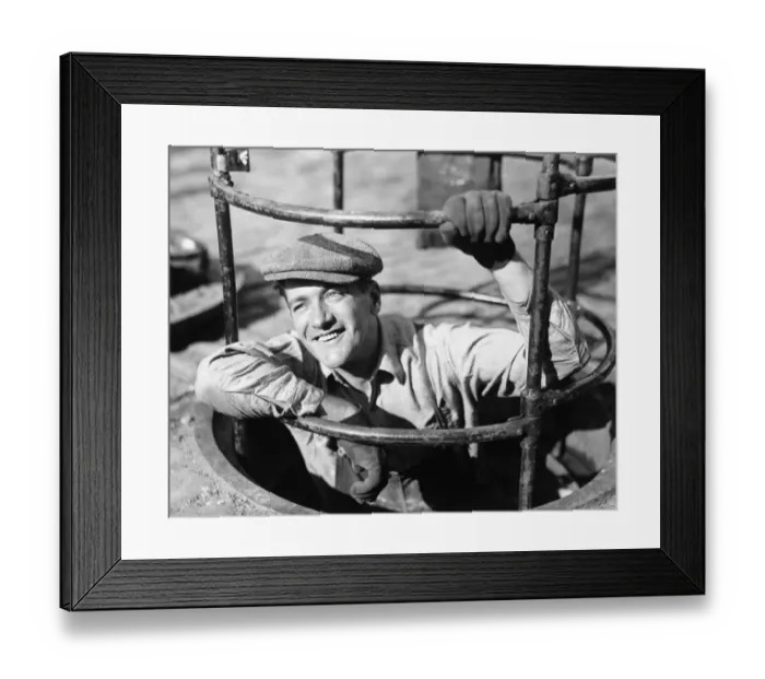 Framed Print : Sewer worker descending below street, (B&W), close-up Framed Print : Sewer worker descending below street, (B&W), close-up