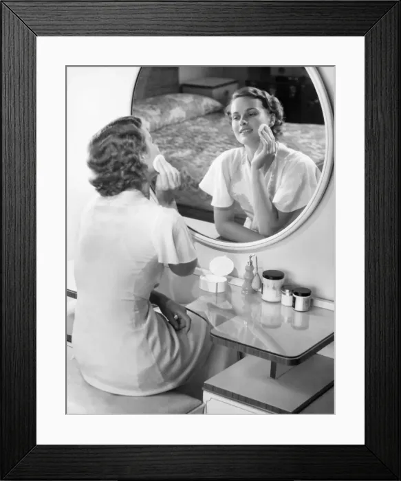 Framed Print : Woman applying powder with powder puff in front of mirror, (B&W) Framed Print : Woman applying powder with powder puff in front of mirror, (B&W)