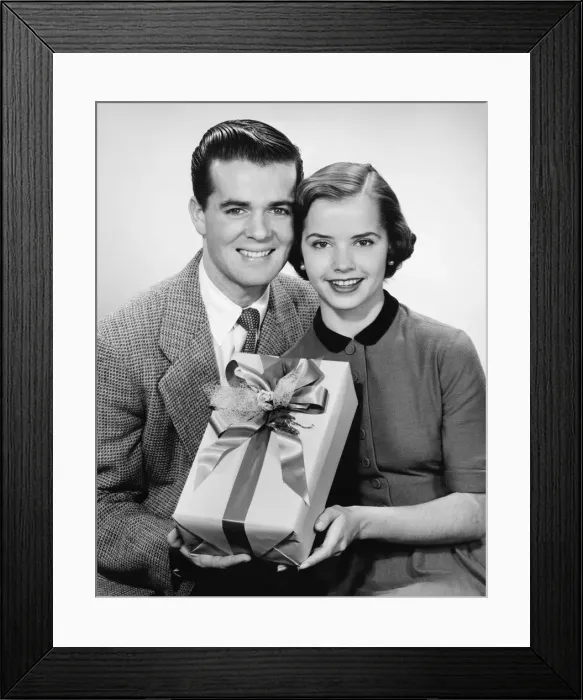 Framed Print : Young couple holding present, posing, (B&W) Framed Print : Young couple holding present, posing, (B&W)