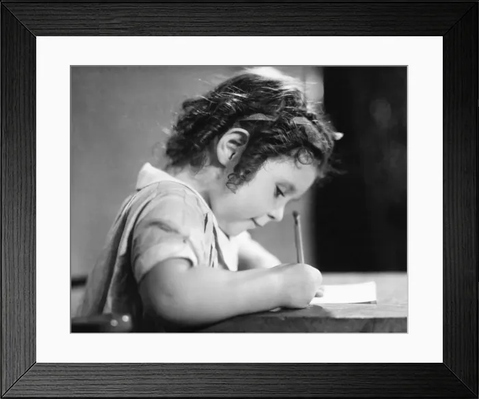 Framed Print : Girl (6-7) writing at table, (B&W) Framed Print : Girl (6-7) writing at table, (B&W)